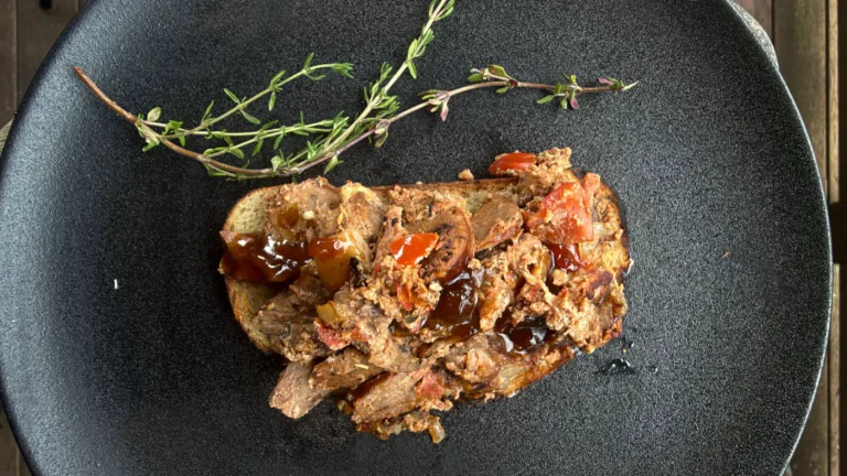 Leftover braai meat with egg and tomato relish piled on buttered braai toast, finished with chutney and fresh thyme