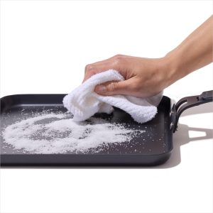 Scrubbing the OXO Outdoor carbon steel griddle with coarse salt and a cloth