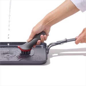 Hand washing the OXO Outdoor carbon steel griddle pan with a brush
